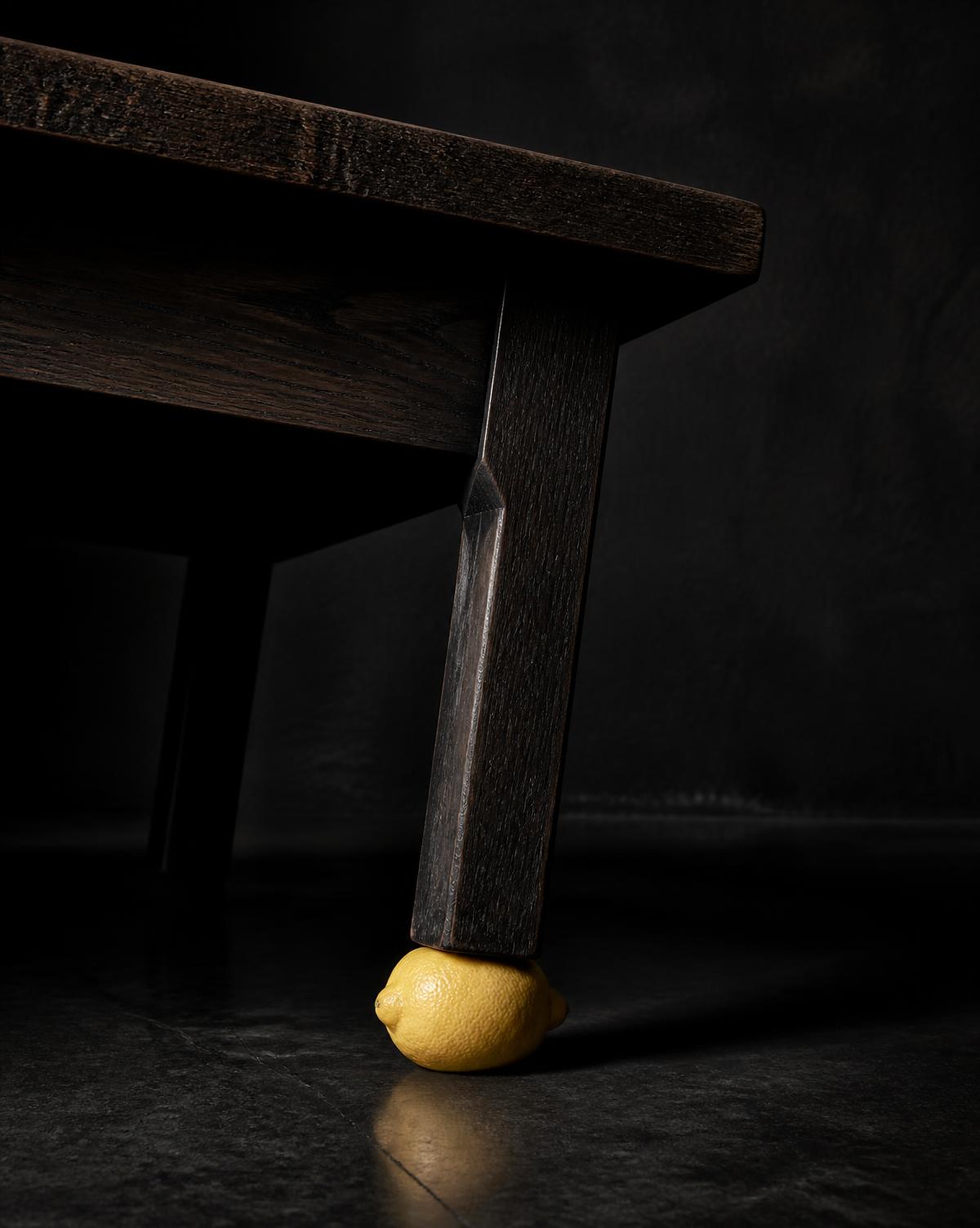 A single lemon wedged under the leg of a heavy dark table, tilting it upward.
